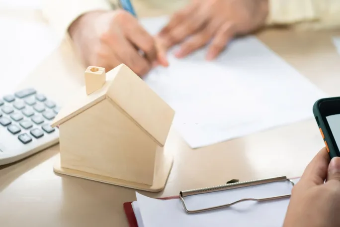 Mortgage paperwork and a model home on a desk