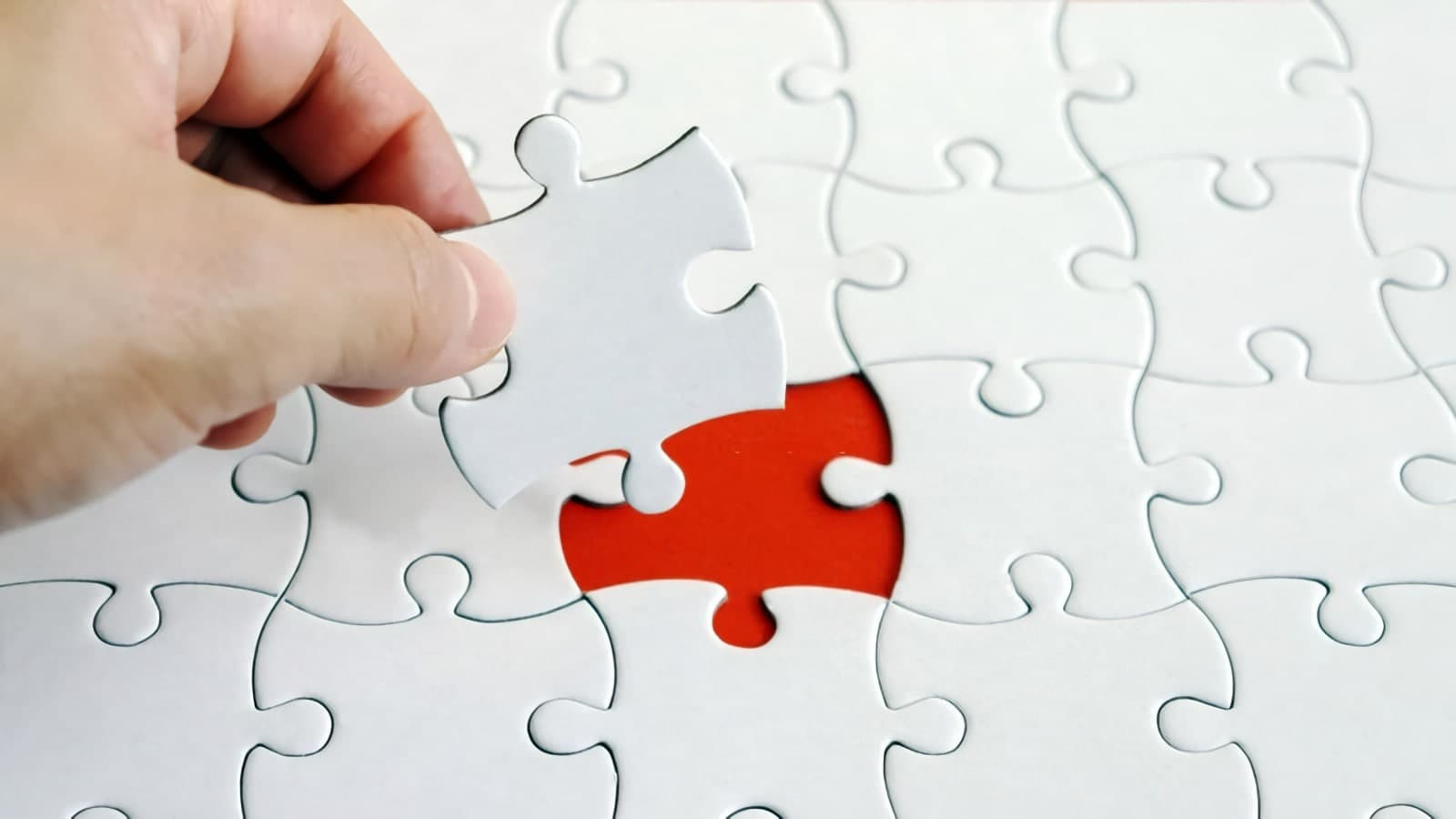 A red puzzle piece being placed into a white puzzle